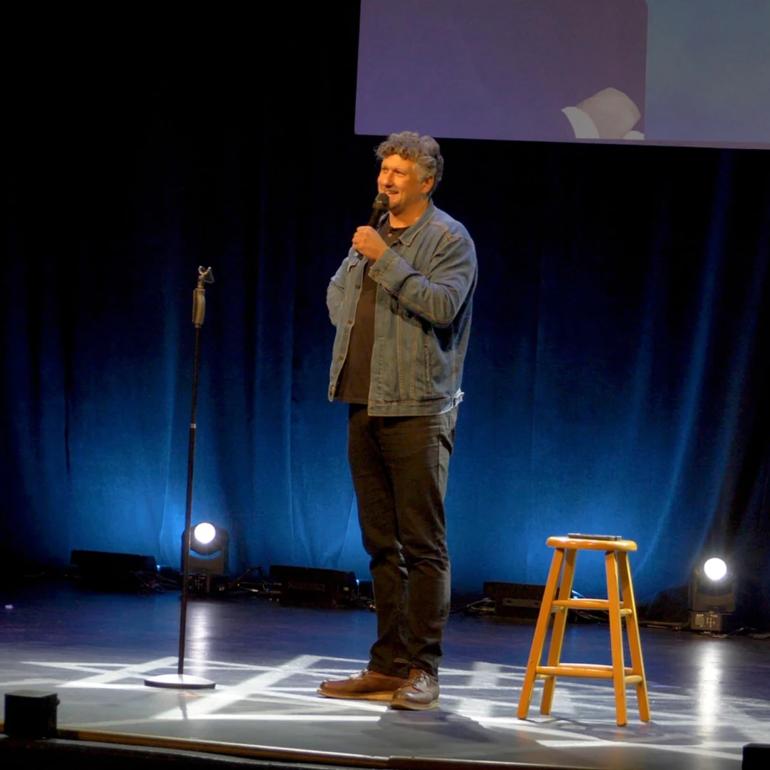 A comedian performing in a denim jacket