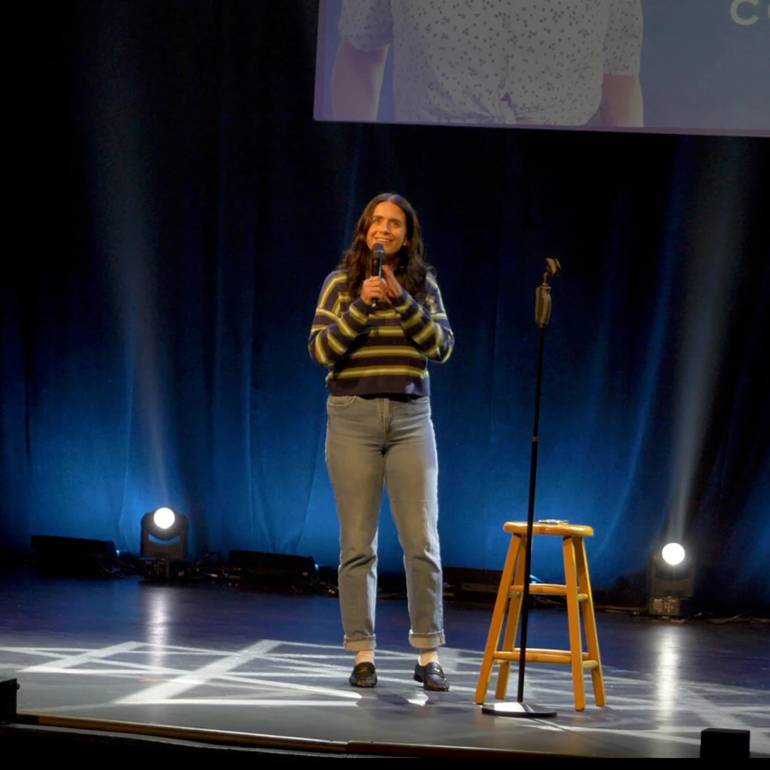A comedian performing in a striped sweater