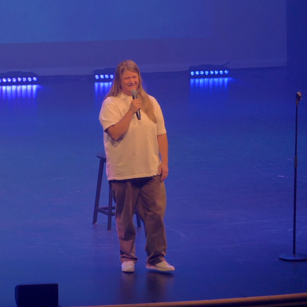 A comedian performing in a white shirt