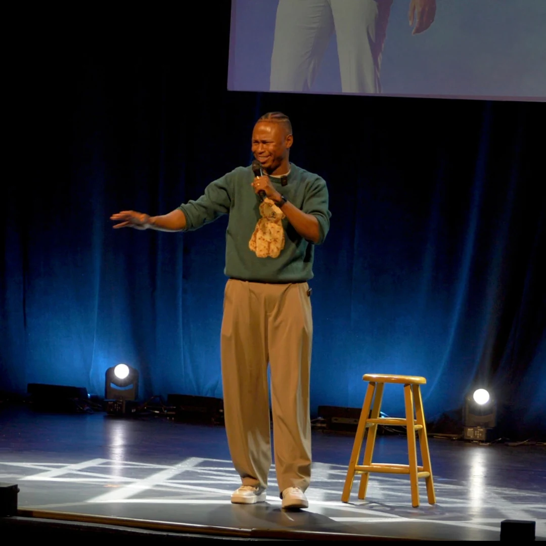 A comedian performing in a green sweatshirt